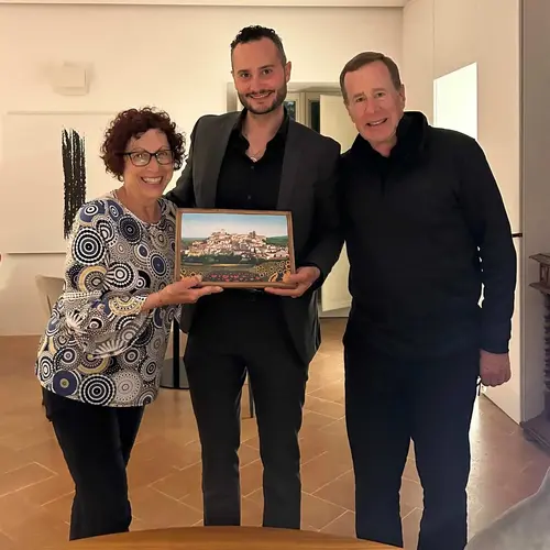 A memorable moment as three individuals pose with a framed painting, celebrating their shared experience and connection to a cherished Italian town.